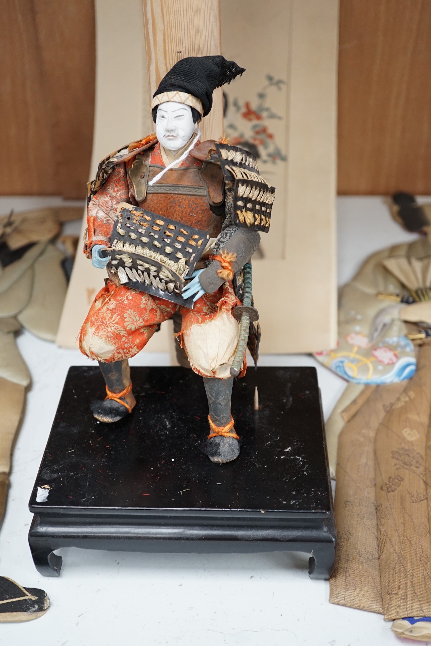 A Japanese seated Samurai figure on stand, two appliquéd fabric figures and a Chinese print, tallest figure 48cms high